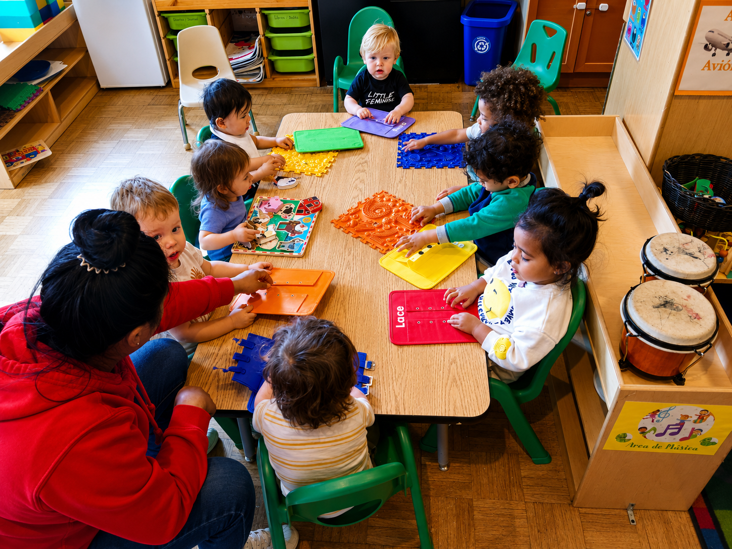 Toddlers working with hands-on learning materials around a table with their teacher