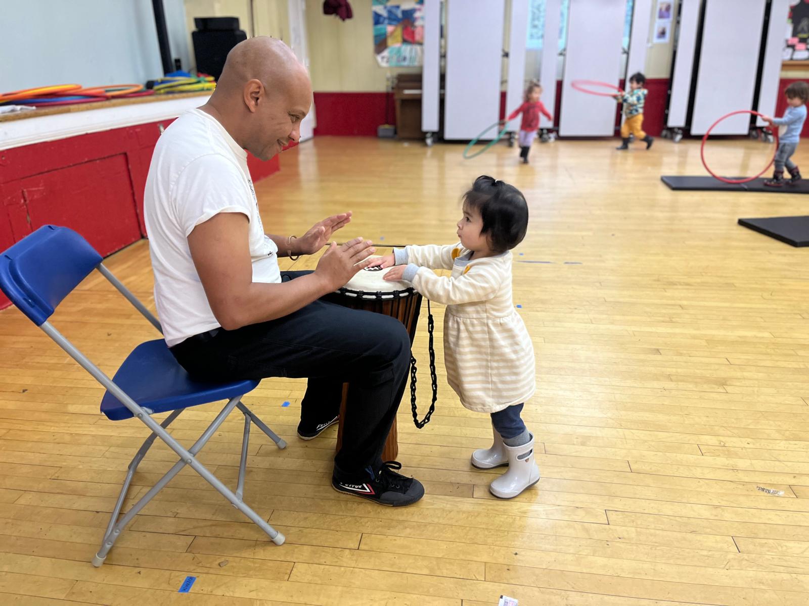 A Capoeira instructor and young child playing a drum together