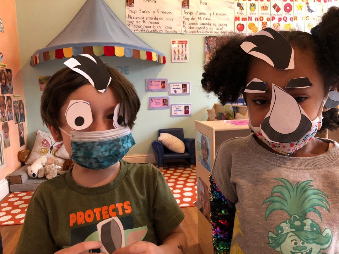 Two Amistad students wearing handmade animal masks they made in class
