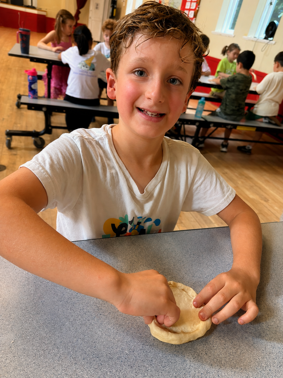 A smiling student shaping dough during a cooking activity