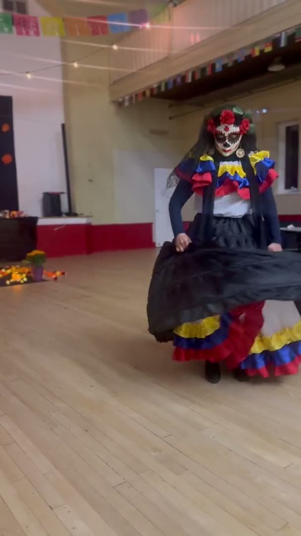 A dancer in a Día de Muertos dress performing in the school gym