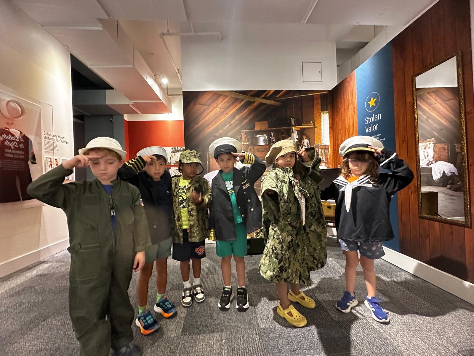 Amistad students trying on uniforms and saluting during a museum field trip
