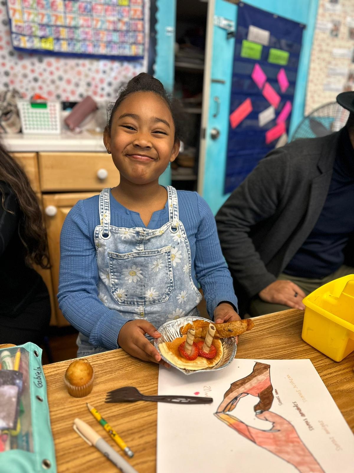 An Amistad student smiling while holding a breakfast plate she decorated in class