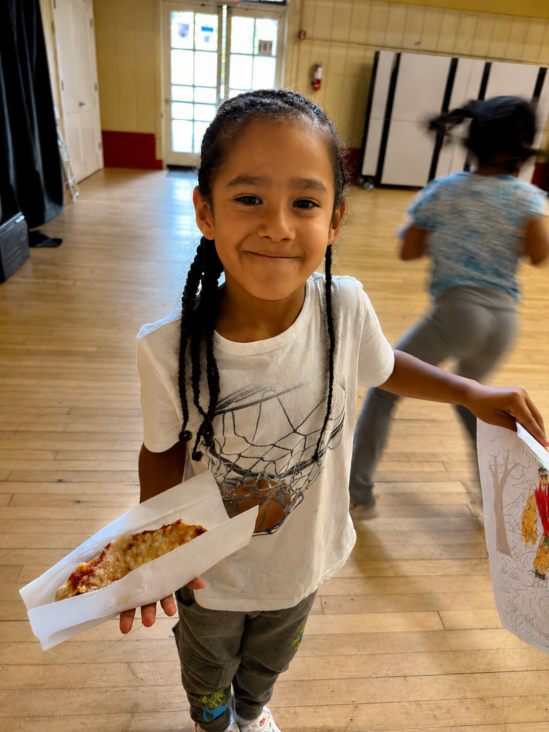 A student proudly showing her pizza and artwork