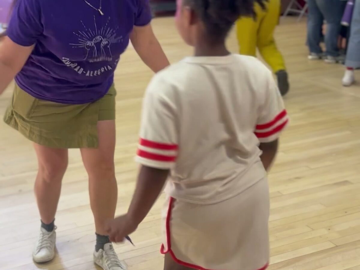 A teacher and student dancing together in the school gym