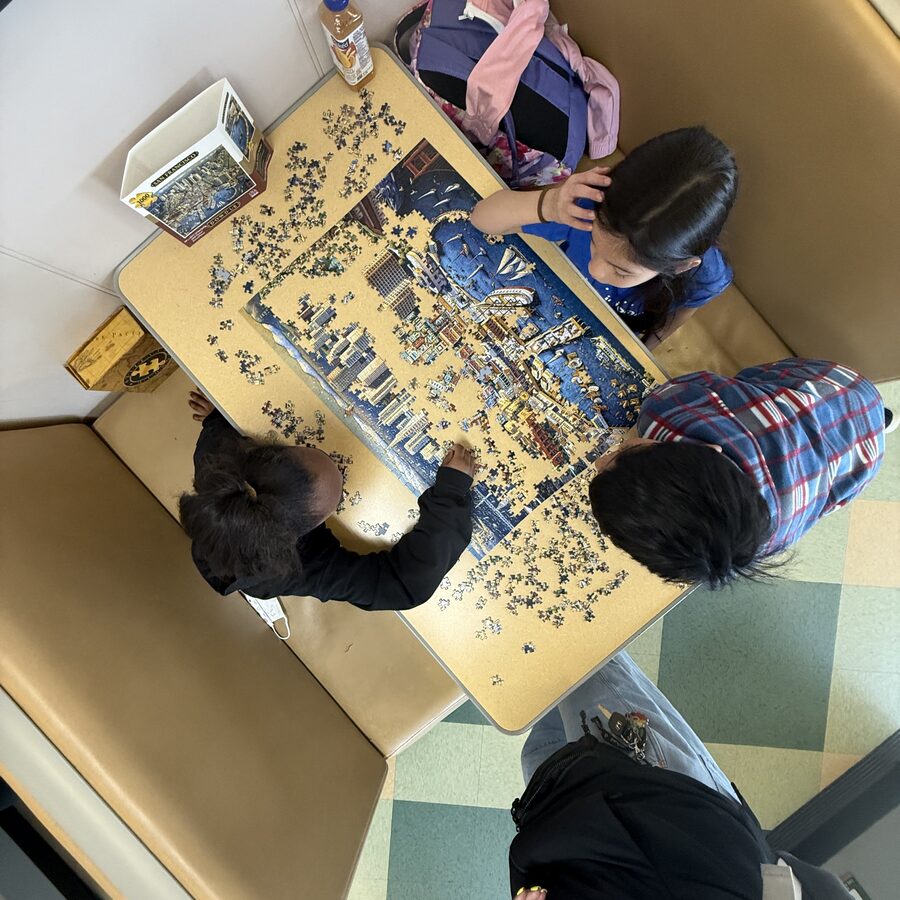 Students working on a jigsaw puzzle together during extended day