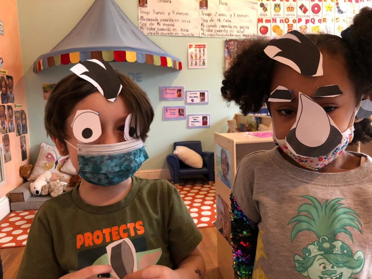 Two Amistad students wearing handmade animal masks they created in class